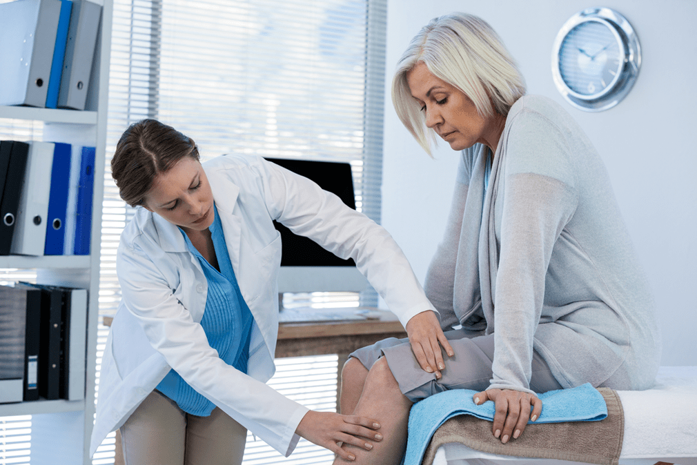 Врач осматривает пациента с остеоартрозом коленного сустава. 